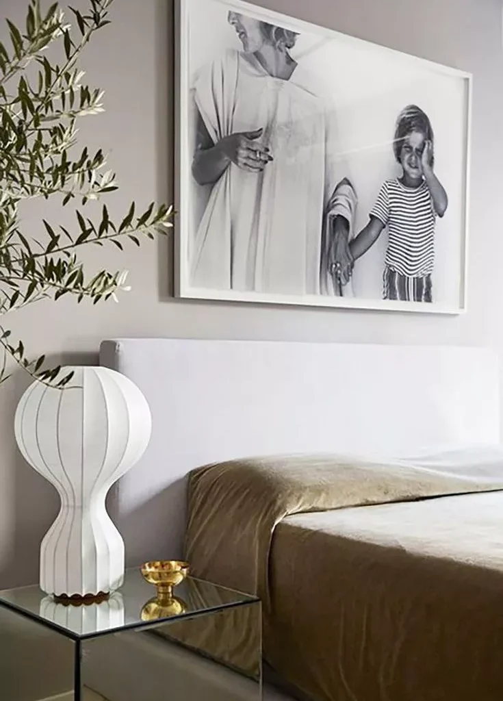 A white bedroom with a bed and picture hanging above Tali Roth