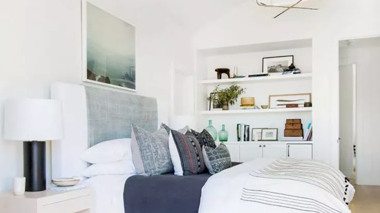 A boho bedroom with large bed with pillows and a shelf