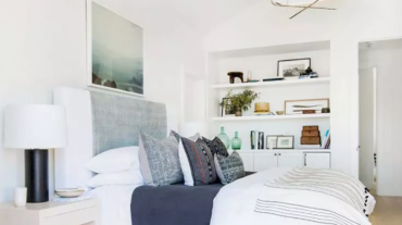 A boho bedroom with large bed with pillows and a shelf